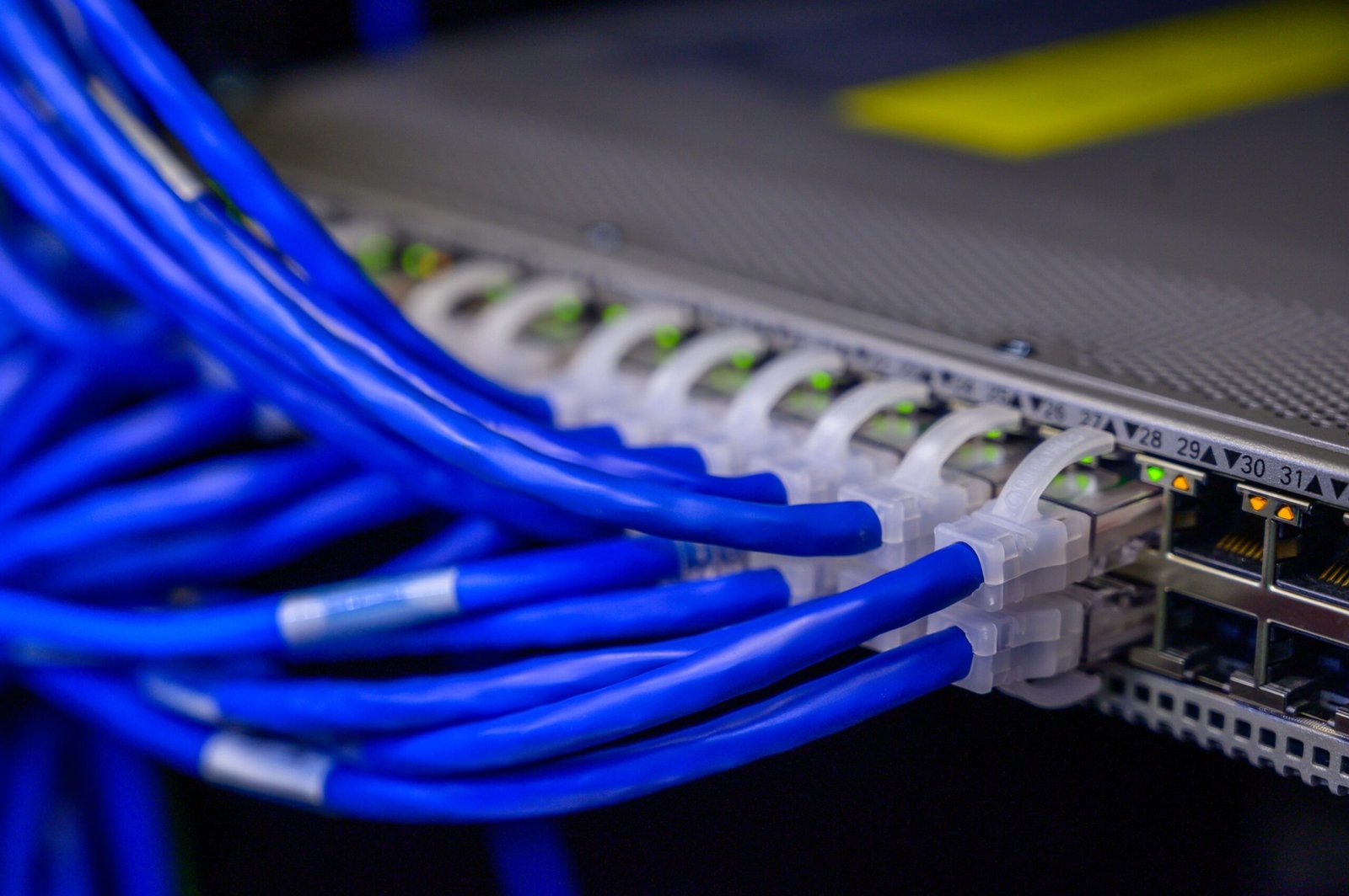 Blue Ethernet cables plugged into a PoE network switch with active link lights